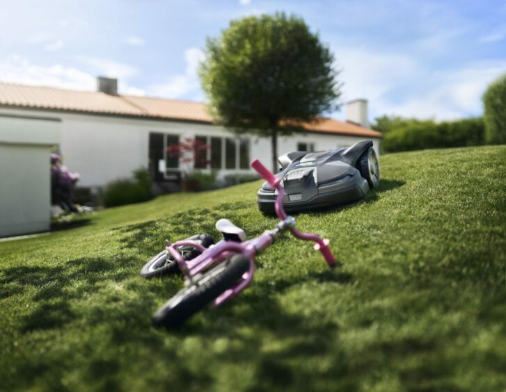 Robot mower approaching a child's bike