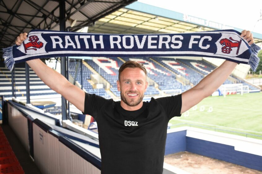 Keith Watson holds a Raith Rovers scarf above his head.