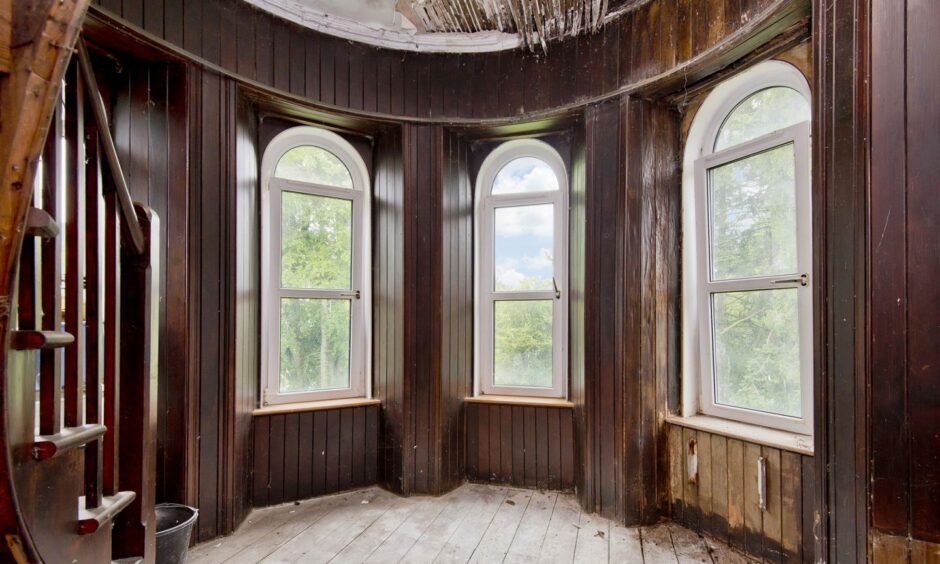 Dunolly House interior, dark wood panelled bay windows looking out to trees beyond