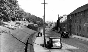 A picture showing the view along Lochee Road in 1957, with the tram lines still in place