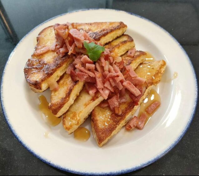A plate full of French toast with bacon and maple syrup.