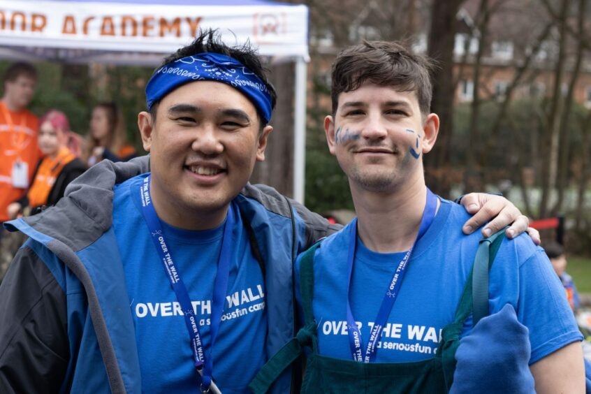 Camp helpers who volunteer at Over the Wall camp. They have face paint and are wearing camp t-shirts. They are smiling at the camera.