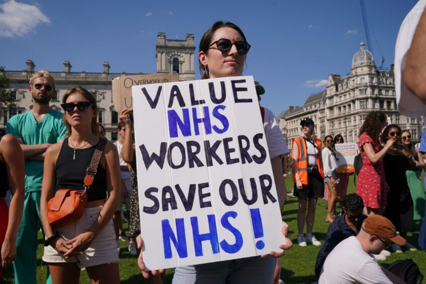 Striking junior doctor holding a home made placard which reads 'Value NHS workers, save our NHS' at a rally in Parliament Square, London.