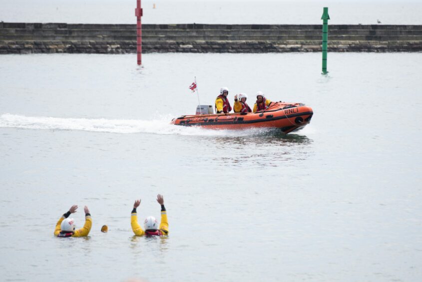 A lifeboat heads for two men in the water as part of the lifesaving demonstration.