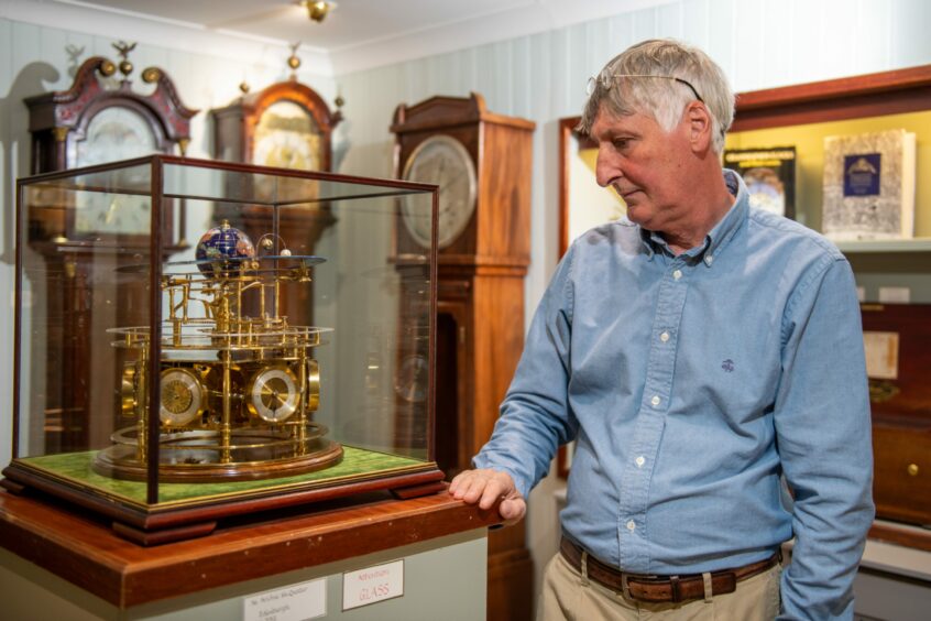 Eric Young in his shop with the display of clocks