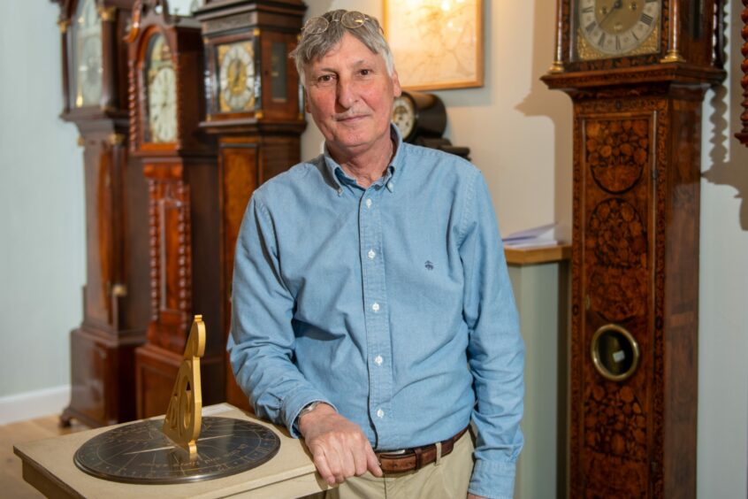 Eric Young in his shop with the display of clocks,