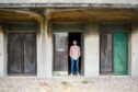 Musician Andy Truscott is standing in the doorway of an abandoned building at Crail Airfield.
