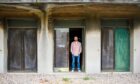 Musician Andy Truscott is standing in the doorway of an abandoned building at Crail Airfield.