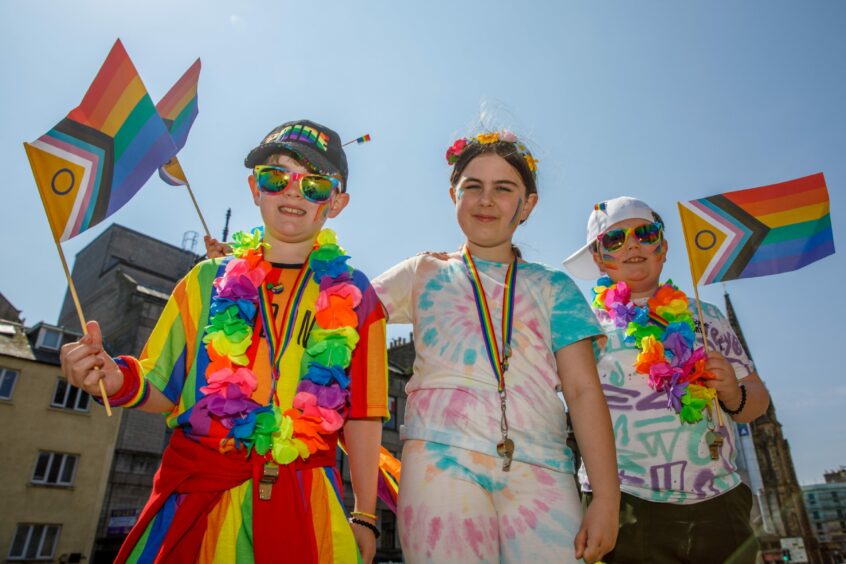 Three children with rainbow flags and clothes in this year's Dundee Pride.