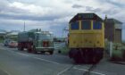 Road traffic waits as this Class 25 diesel crosses the A92 at Arbroath beside Elliot signal box. Image: Brian Livie.