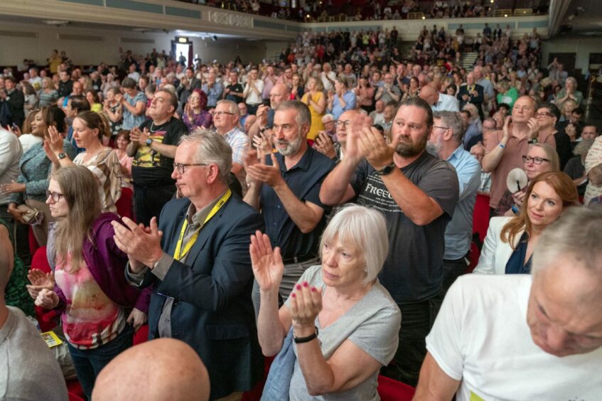 Large crowd of Scottish independence supporters on their feet applauding while Humza Yousaf addresses the audience at the SNP independence convention in the Caird Hall, Dundee.