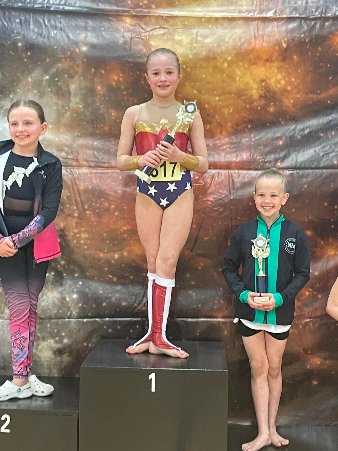 Larissa Wernsen from Inspire Dance Studio on a podium holding her trophy.