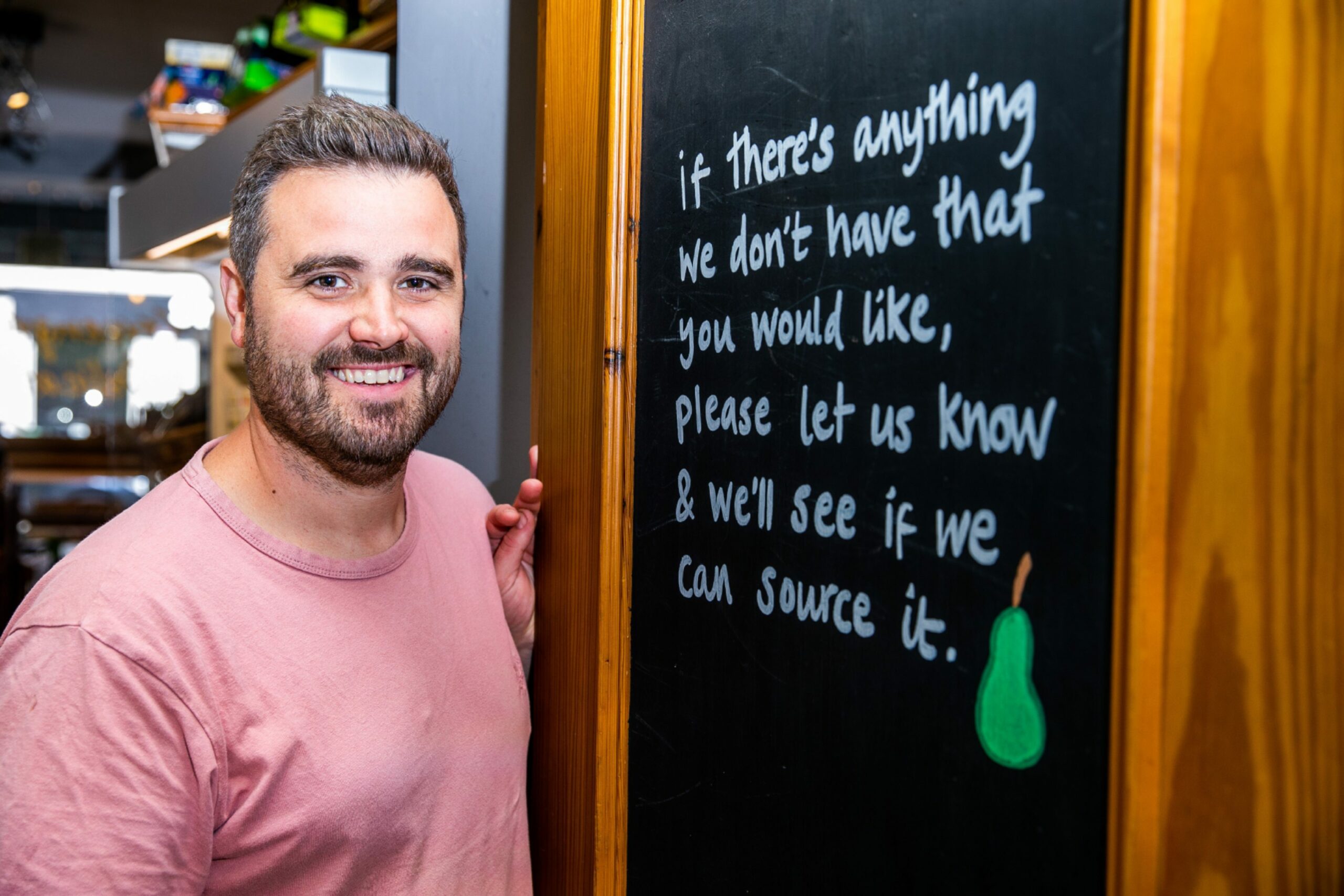 Fraser Reid in his Dundee shop standing beside a chalk board.