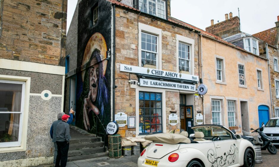 Tourists stop to look at the Pittenweem witch mural. 