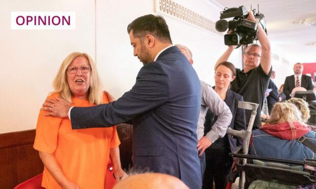 Humza Yousaf with his hand on the shoulder of protester Theresa Mallet after she disrupted his speech to the SNP independence convention in Dundee's Caird Hall.