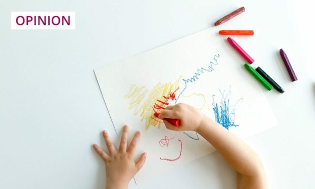 small child drawing with crayons, photographed from above.