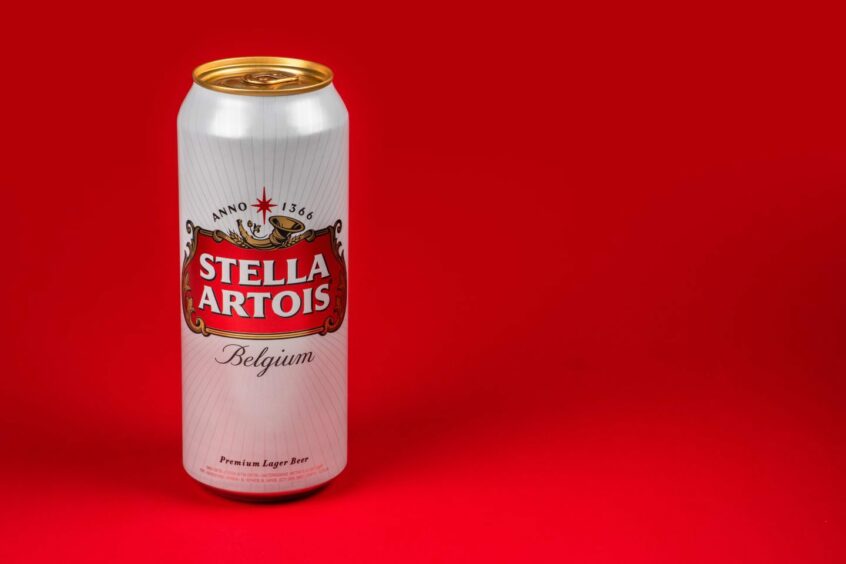 Single can of Stella Artois on red background.