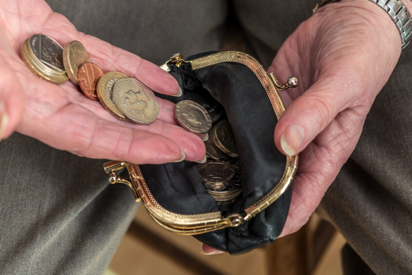 A photo of an open purse and money in a elderly person's hand.