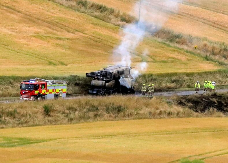 Crews tackling the combine harvester fire on the A92 with white smoke billowing from the vehicle