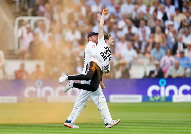 England's Jonny Bairstow removes a Just Stop Oil protester who has thrown orange dust onto the pitch during an Ashes test match at Lord's, London.