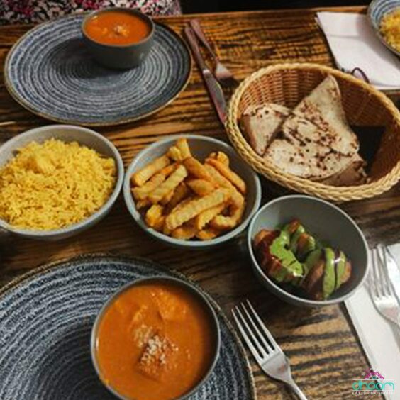 a table laden with plates of Indian dishes including saffron rice, curry and naan bread