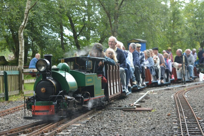 Miniature train with passengers of all ages aboard it at Wester Pickston railway centre.