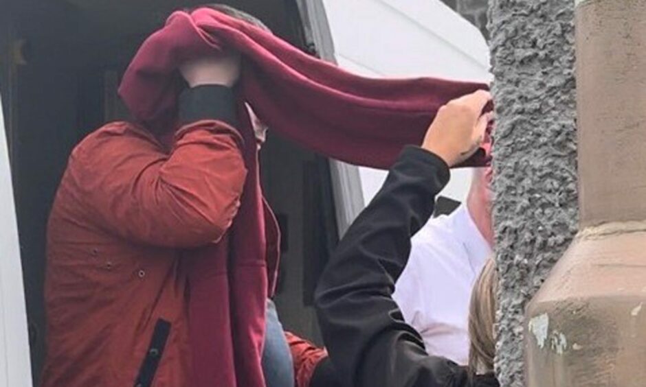 Officers from GEOAmey, which apologised for delaying the start of his trial, help cover Dean Stirton's face as he arrives at Perth Sheriff Court.