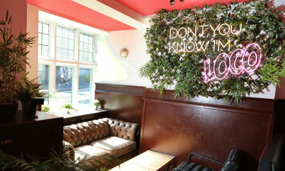 A sunny corner of Loco Rita's in Dundee with a neon sign saying "don't you know I'm loco" hanging on the wall.