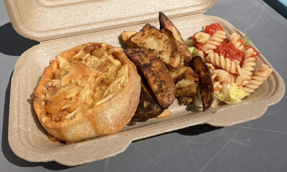 A takeaway box with a macaroni pie, wedges and salad.