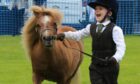Smiling Rory Andrews running round show ring with tiny Shetland pony.