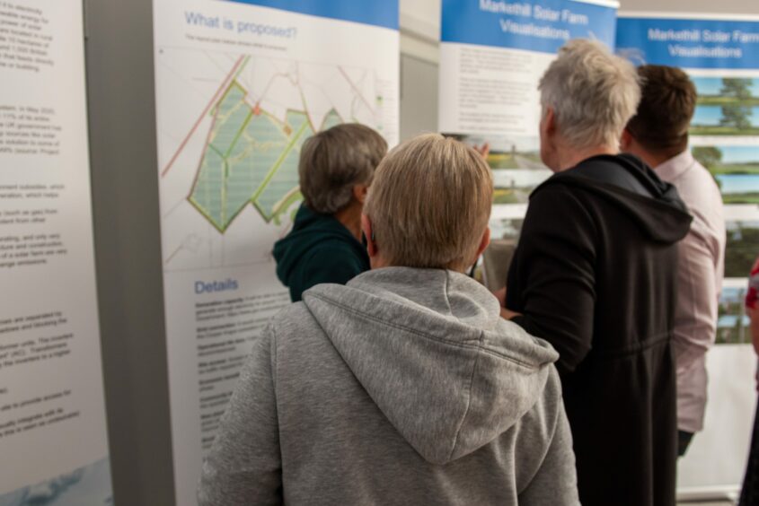 People viewing maps and plans at a consultation event for the Coupar Angus solar farm