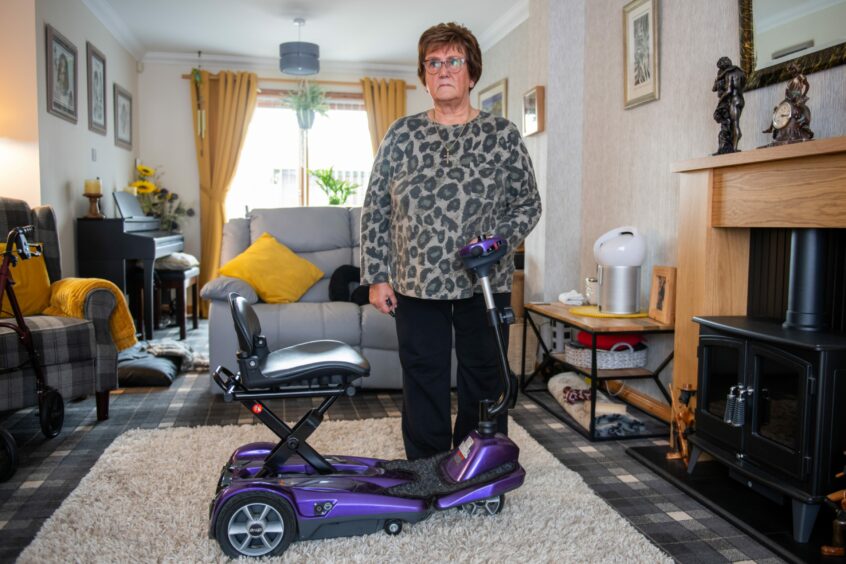 Doreen Bruce standing in her living room with her mobility scooter