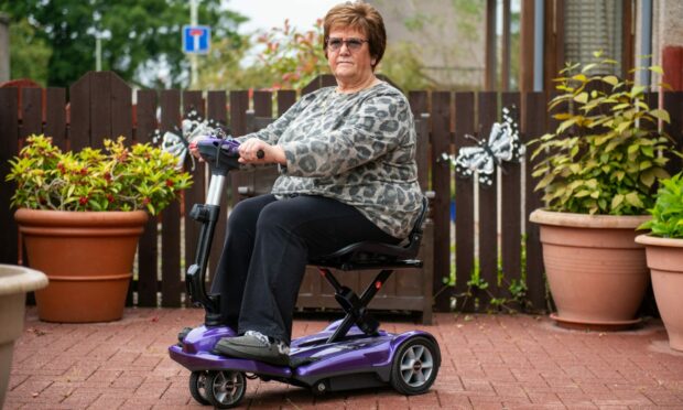 Doreen Bruce on her mobility scooter outside her home in Downfield, Dundee