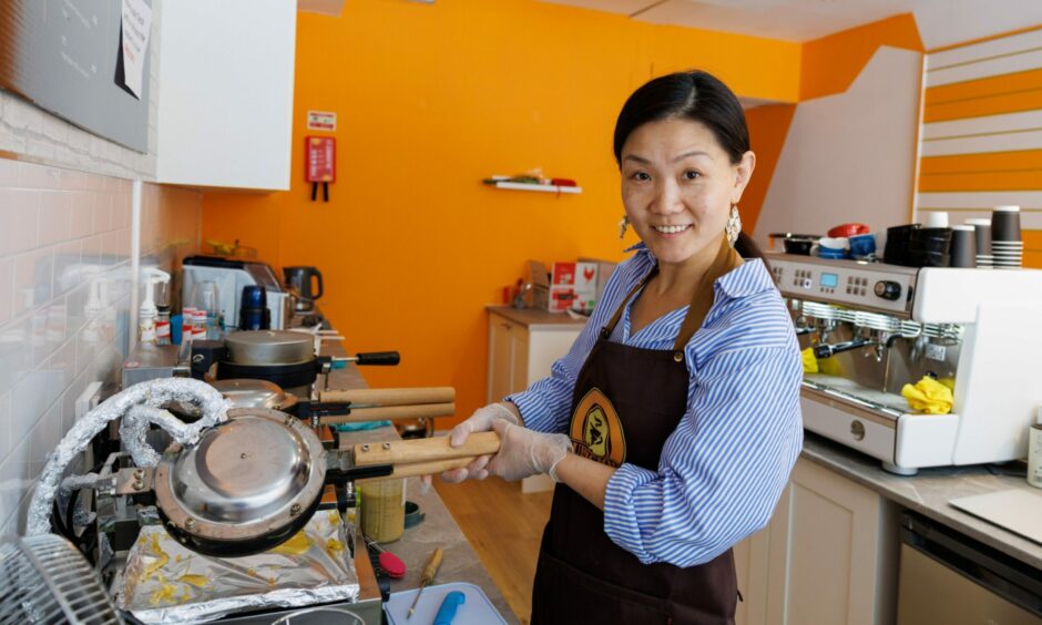 Cafe owner Yu wearing a Bubblicious Dundee apron operates the bubble waffle maker.