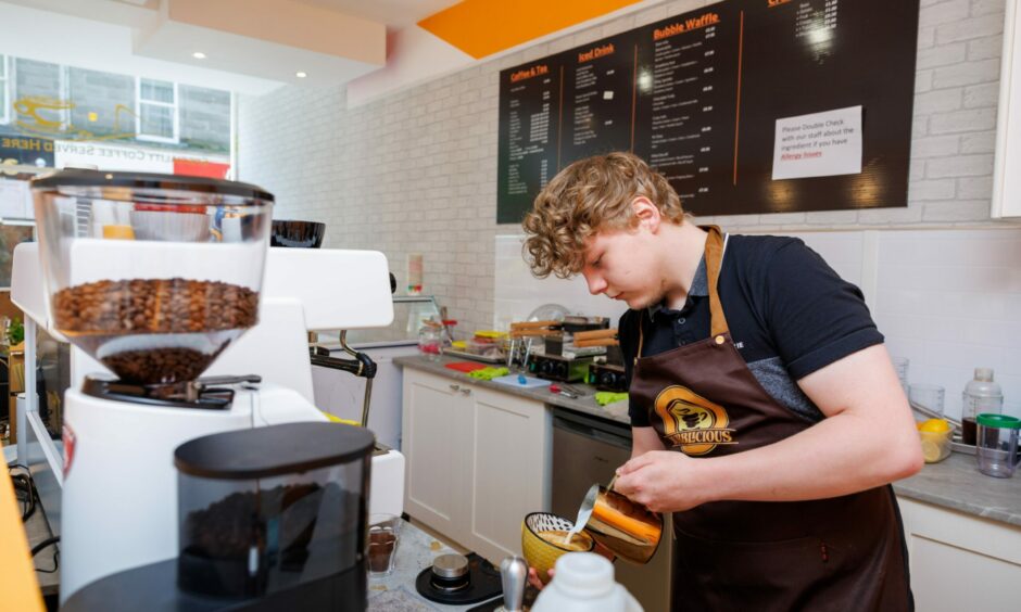 A barista pouring a coffee with latte art.