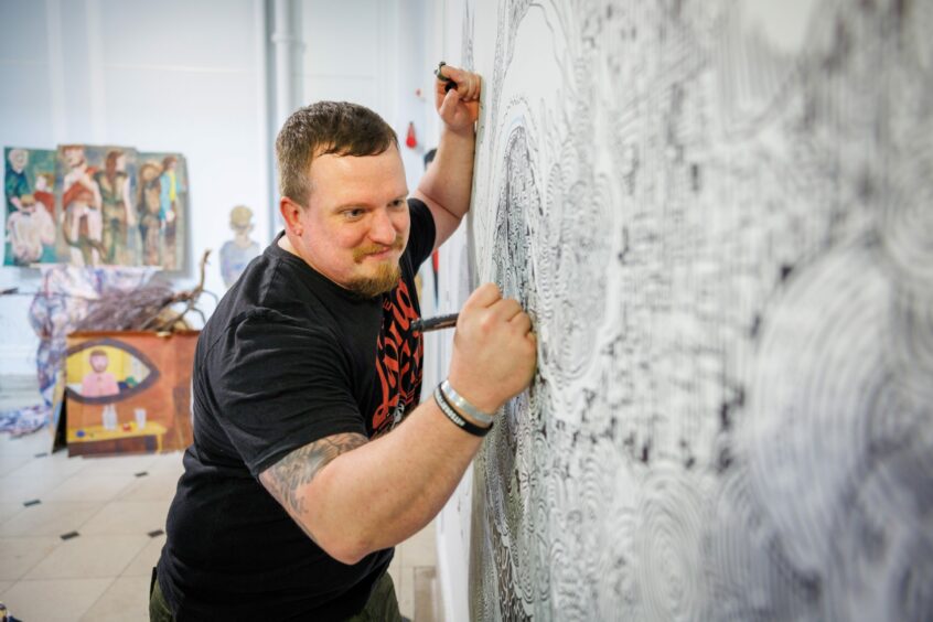 Grum Murtagh draws on a plain wall within the gallery space which when finished will be painted over again. 
