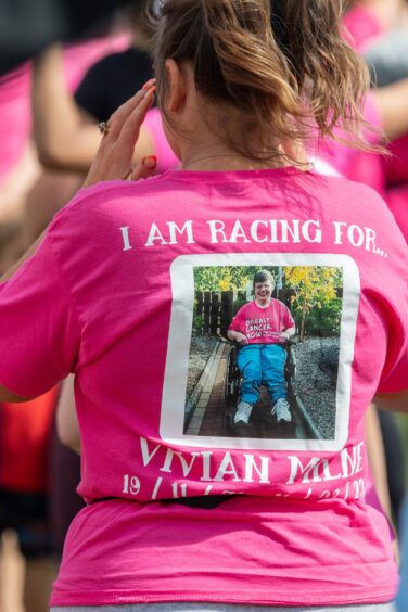 woman wearing a pink T shirt with a photo on the back and the words 'I am racing for Vivian Milne'.