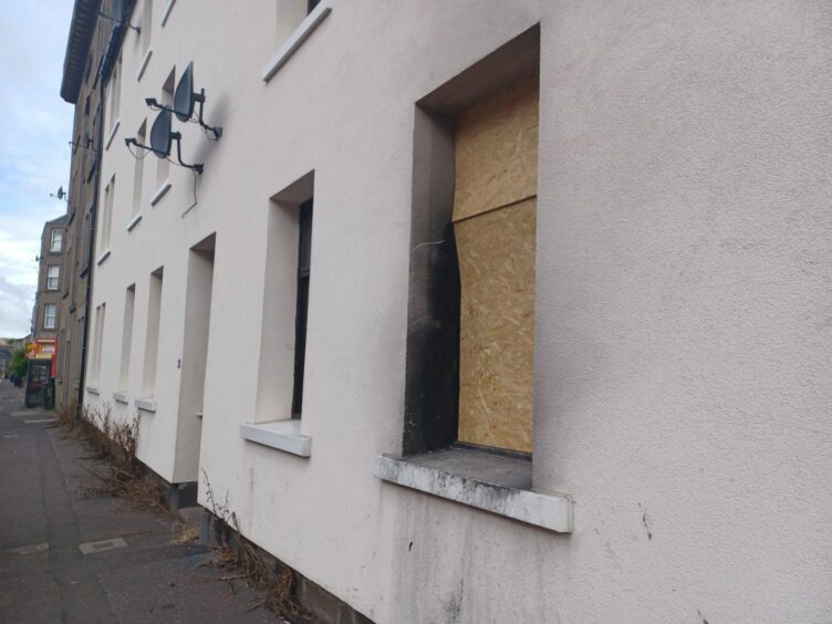 The boarded-up window of a flat on Cleghorn Street after a fire