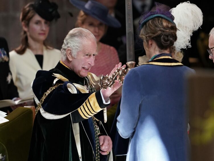 King Charles III in long cape, touches the Elizabeth Sword, held by Dame Katherine Grainger during the service at St Giles' Cathedral, Edinburgh