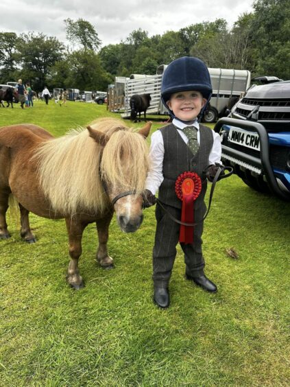 Rory Andrews, 5, in tweet trousers and waistcoat with Shetland pony and a red rosette round his waist.