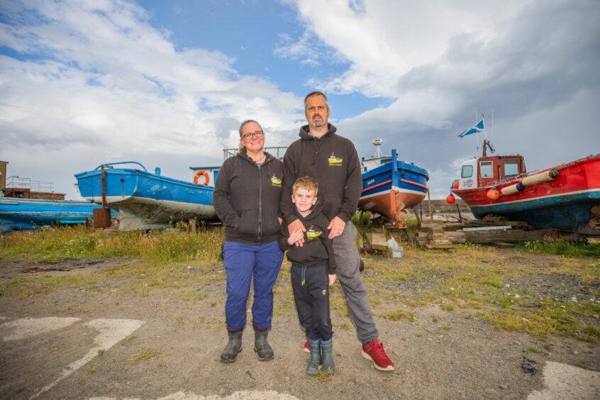 Tina and Ross Coventry and son James in front of boats in Methil