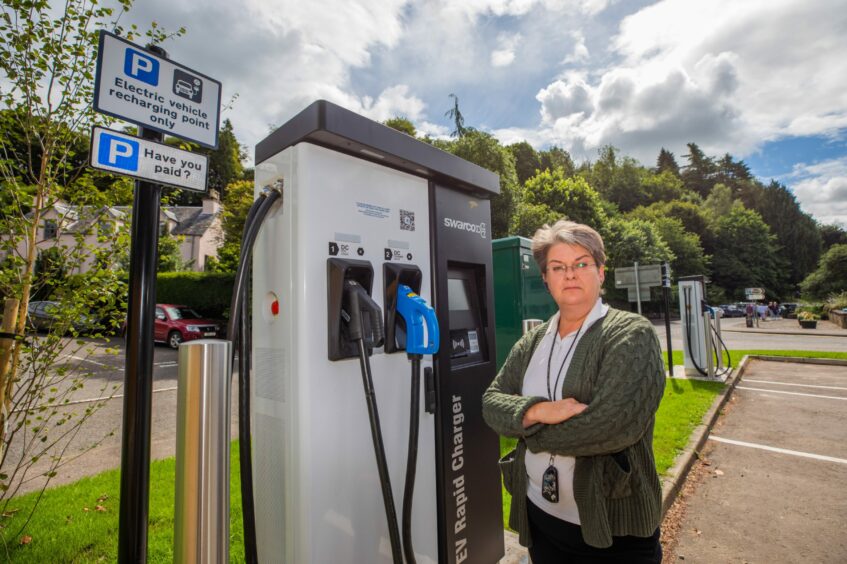 Marian stands with her arms crossed beside the Dunkeld EV chargers.