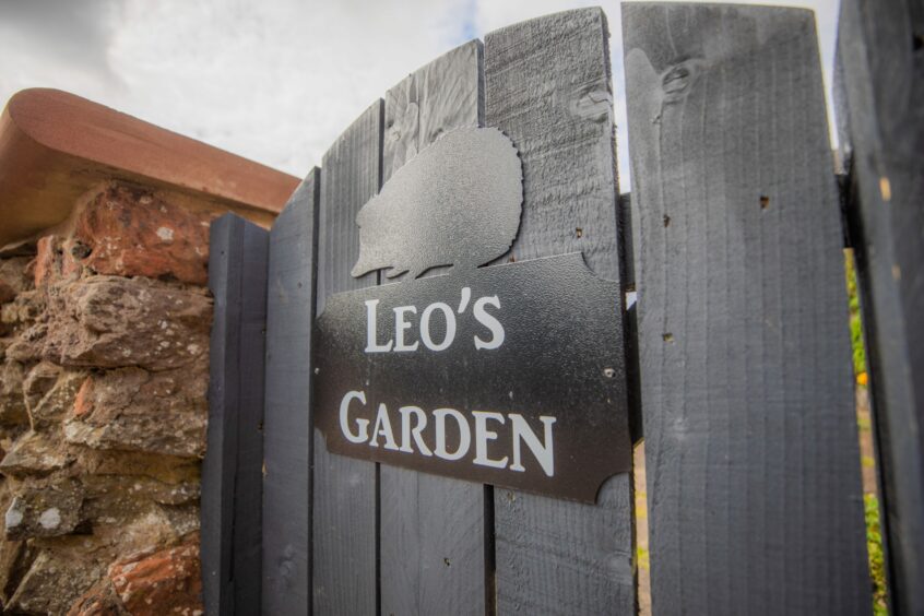 Black painted garden gate with a sign depicting a hedgehog and the words 'Leo's garden'