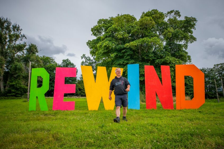 Rewind Scotland producer Steve Porter walking away from the colourful Hollywood-style Rewind sign at Scone palace.