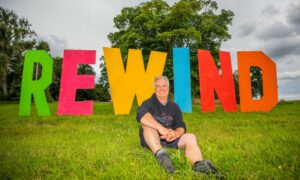 Steve Porter seated in front of Rewind festival sign at Scone Palace.