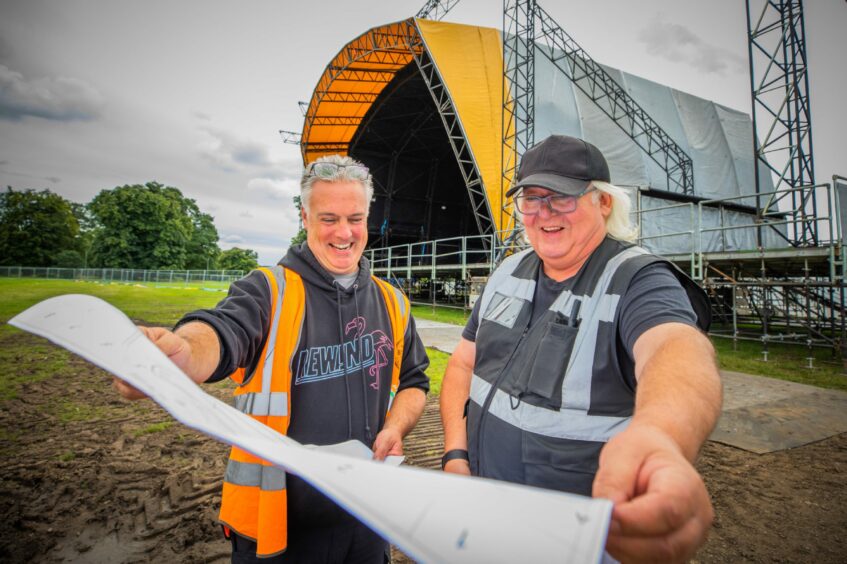 Rewind festival producer Steve Porter and manager Keith Morris reading a site map in front of the main stage at Scone Palace.