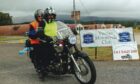 Photo shows Rod and Helen Towers on their vintage Matchless G11 motorbike at a vintage motorcycle club rally. booth wear high-vis clothing and helmets. The bike has a burgundy tank.