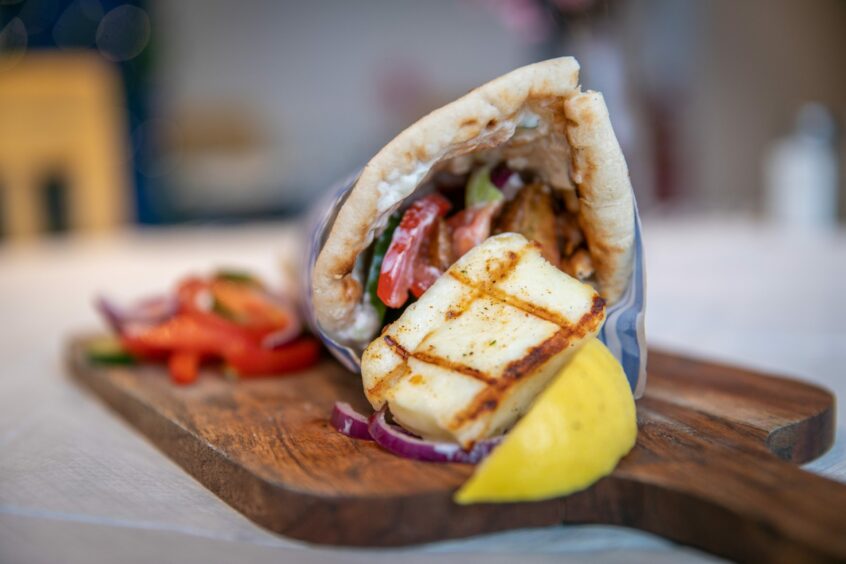 A gyros with a large slice of halloumi lying on a wooden board in Andreou's Dundee.