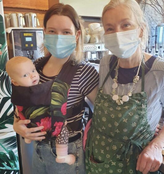 Zoe holding five-month-old Lily and her mum Jane in the cafe. 