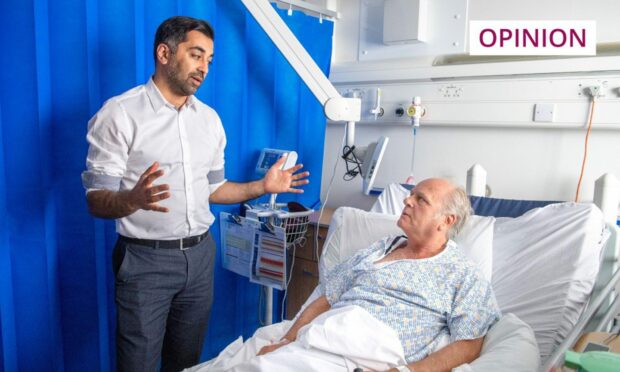 First Minister of Scotland Humza Yousaf at the hospital bedside of an elderly man during a visit to mark the 75th anniversary of the NHS.